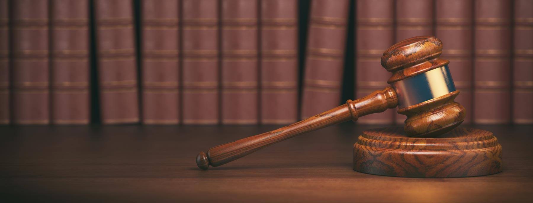 wooden gavel in front of shelf of hard covered books